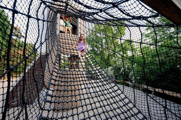 Kids playing in rocket slide ropes at children's playground in public park