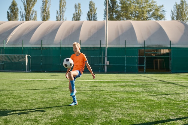 Kids playing soccer game, young boy footballer wearing uniform hitting ball