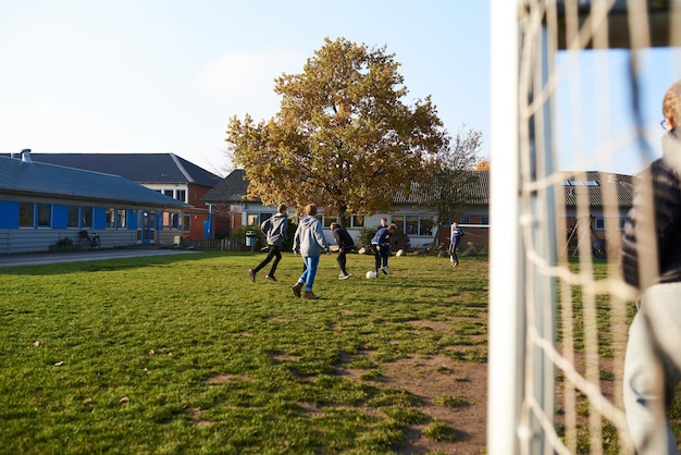 学校の遊び場でサッカーをしている子供たち