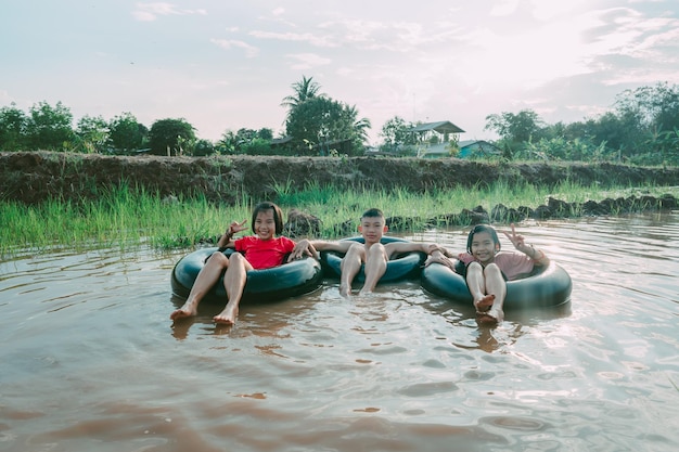 Kids playing and swimming in canal of organic farm in countryside