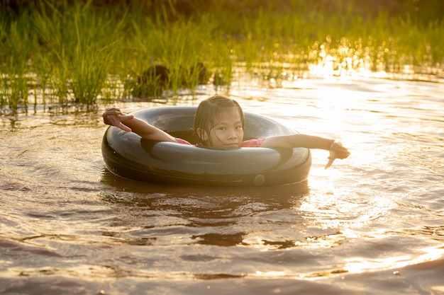 Bambini che giocano e nuotano nel canale dell'azienda agricola biologica in campagna