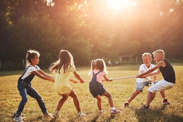 Photo kids playing tug of war game in the beautiful meadow at sunny day.