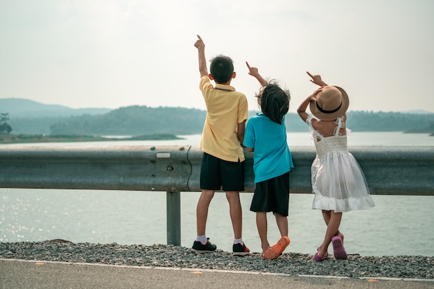 Kids point to sky on beautiful view of dam