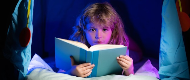 Kids reading a book in the dark home child boy reading a book lying on the bed dreaming child read b