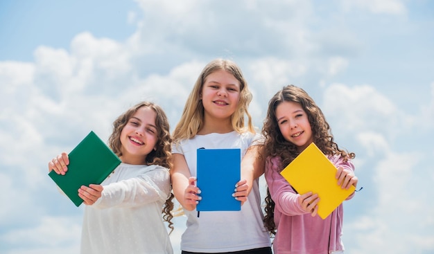 Kids reading books three girls writing in notebook back to school write memories in diary Education and school concept School students learning literature Lost in fairytale