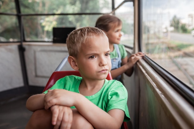 Kids ride in empty tram and look at the window attentively public transportation city tramway