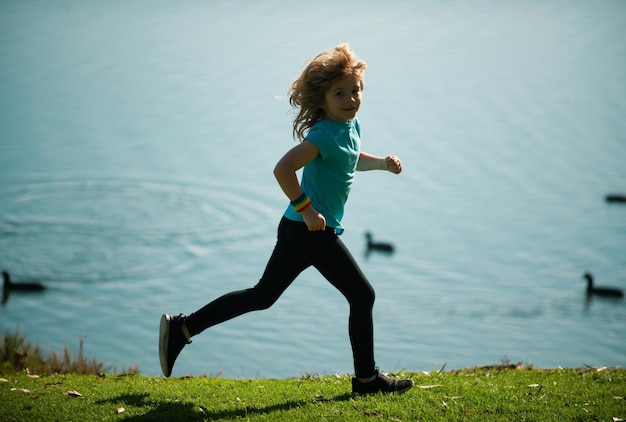 Foto bambini che corrono all'aperto corsa e sport salutare per bambini bambino che corre sul campo estivo vicino al lago kid