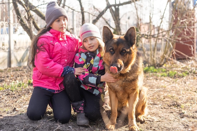 Bambini che corrono con il loro cucciolo di pastore tedesco nel parco