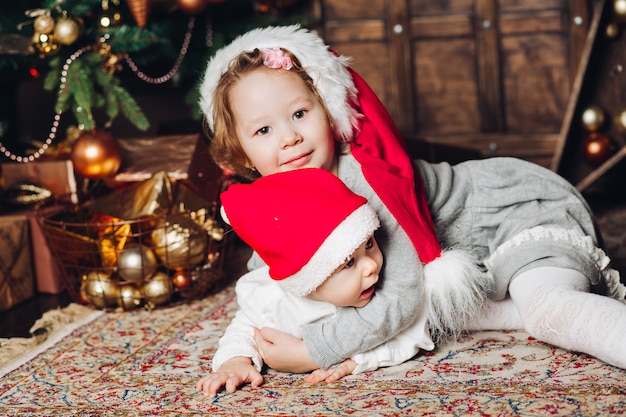 장식 된 전나무 나무에 카펫에 산타 모자에있는 아이.