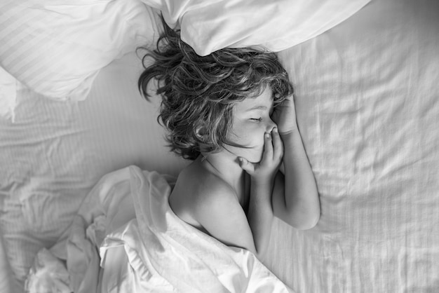 흰색 시트와 베개가 있는 침대에서 자고 있는 침실에 있는 아이