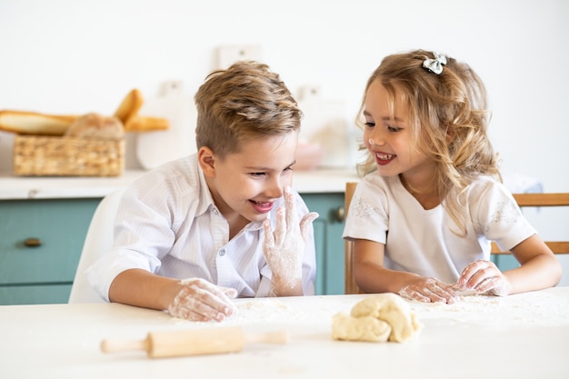 Bambini che sorridono mentre si prepara l'impasto per dolci a casa