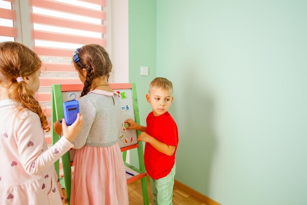 子供たちはプラスチック磁石の数字の助けを借りて数学の問題を解決します。学校に戻る。