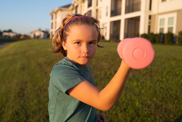 Kids sport training outdoor Child boy raising a dumbbell Cute child training with dumbbells Kids fitness Kid boy exercising with dumbbells Healthy kids