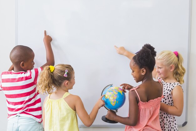 Kids studying globe in classroom