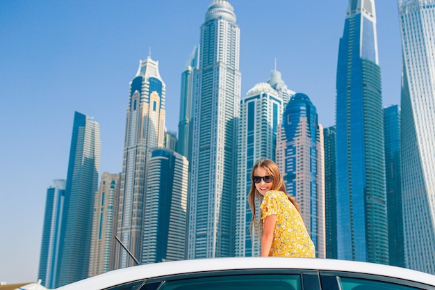 Kids summer vacation. Teenager girl on car vacation over skyscrapers in Dubai