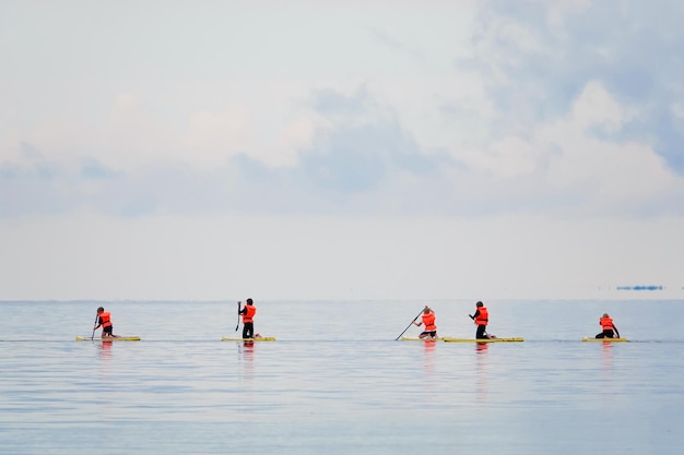 Scuola di surf per bambini al mare blu bambini con insegnante su tavole da surf diretti al surf in uniforme