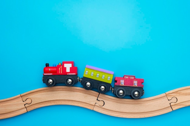 Kids toy train with two carriages on wooden railway on blue background