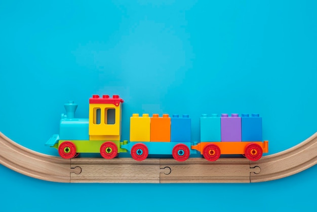 Kids toy train with two carriages on wooden railway on blue background