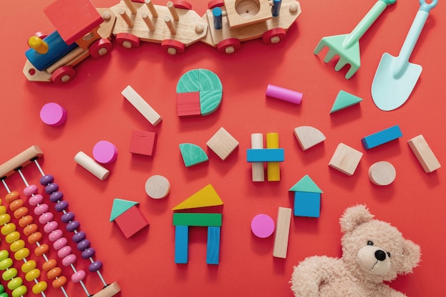 Фото Детские игрушки плюшевые деревянные красочные блоки и поезд на красном фоне