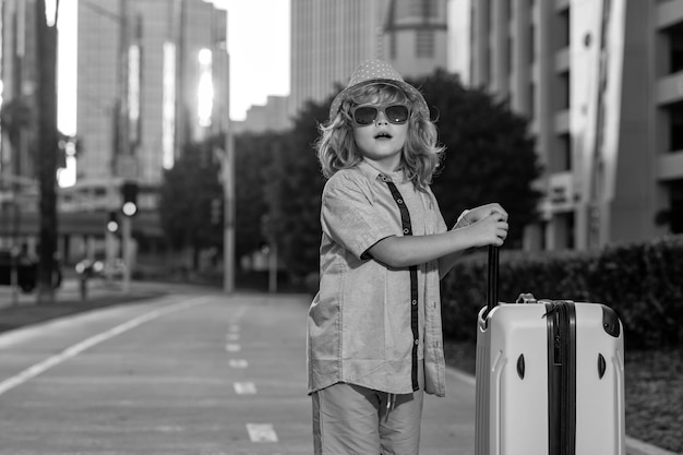 Foto viaggio per bambini bambino felice che trasporta valigie da viaggio all'aperto sulla strada della città stile di vita di viaggio e sogni di viaggio