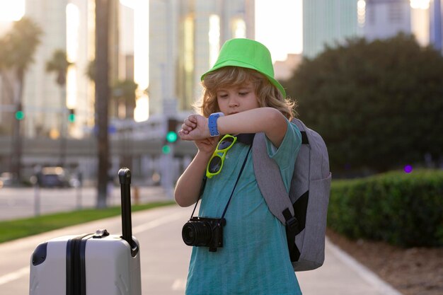 Kids travel Happy child boy carrying travel suitcases outdoor on city street Travel lifestyle and dreams of travel