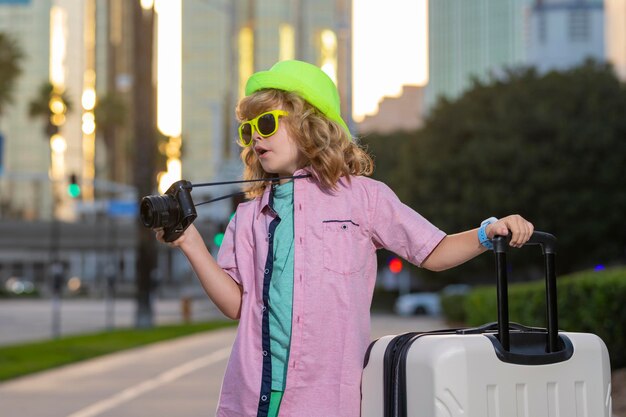 写真 子供たちは旅行する街の通りで屋外旅行スーツケースを運ぶ幸せな子供の少年旅行のライフ スタイルと旅行の夢