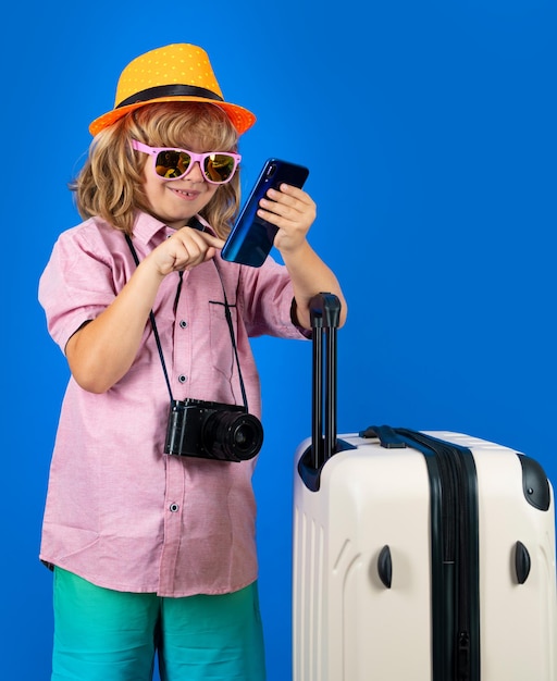 Kids travel Happy child boy in travel hat with suitcases isolated on studio backgraund Travel lifestyle and dreams of travel