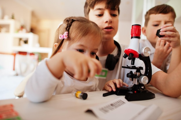 Bambini che usano il microscopio imparano la lezione di scienze a casa.