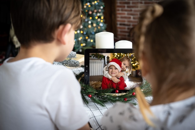 kids video calling winter little boy santa hat computer screen chatting online christmas eve home