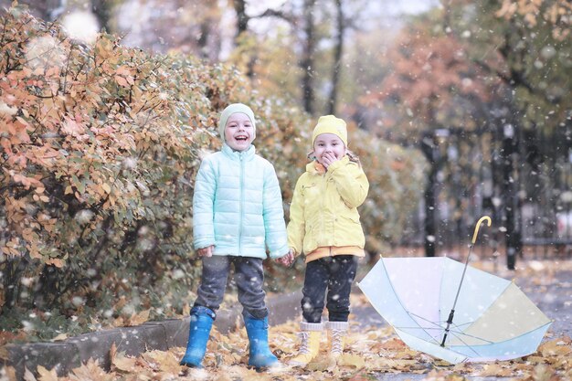 子供たちは公園の最初の雪を歩く