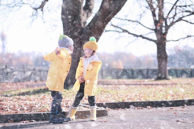 子供たちは公園の最初の雪を歩く