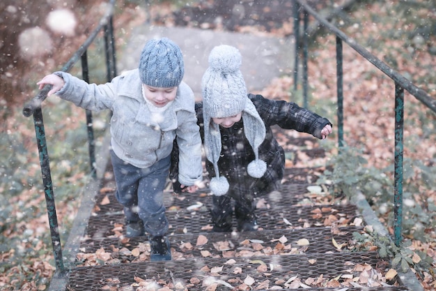 子供たちは公園の最初の雪を歩く