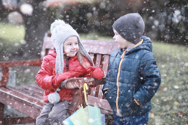 子供たちは最初の雪で公園を歩く