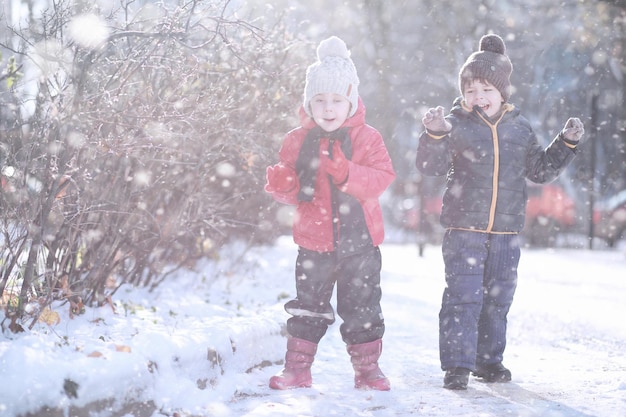 子供たちは最初の雪で公園を歩く