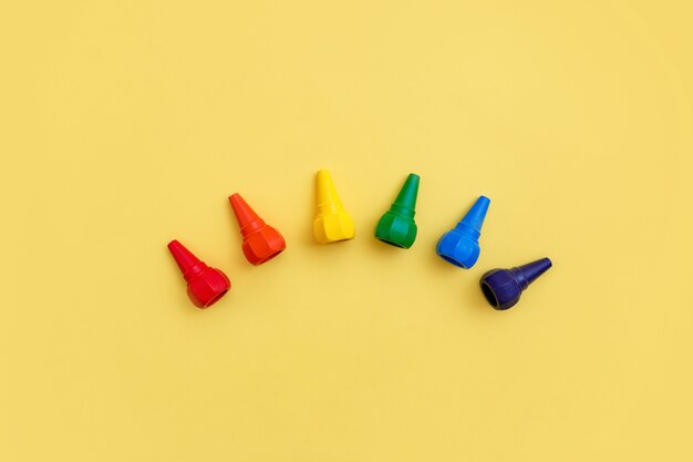 Kids wax crayons on bright yellow backgrouns. Top view.