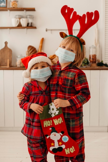 Foto bambini con mascherina medica in possesso di un calzino di natale