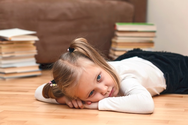 Kidtired van thuisonderwijs Vermoeid kind thuis op een achtergrond van boeken