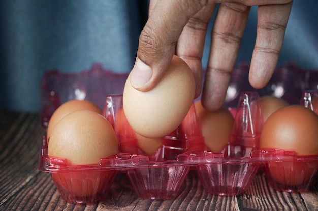 Kies eieren met de hand uit een plastic kist op tafel