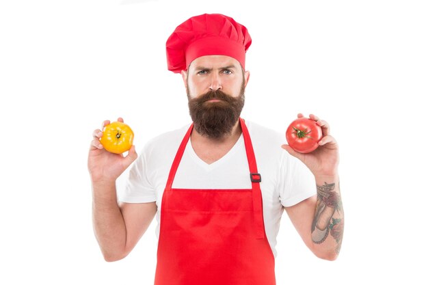 Kies er een Gezond kookconcept Man met baard op witte achtergrond Chef houdt tomaten Kok in uniform houdt groenten Tomatensausrecept Rijpe tomaat voor heerlijke maaltijd Eet verse tomaat