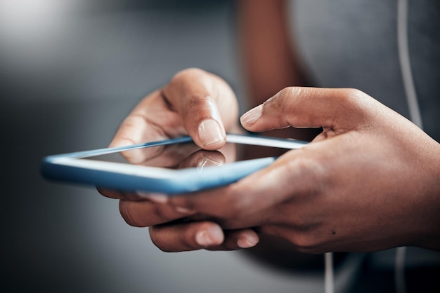 Kies je muziek terwijl je je outfits doet Bijgesneden opname van een onherkenbare jonge vrouw die haar mobiele telefoon gebruikt in de sportschool