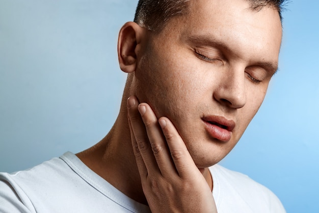 Kiespijn. Portret van een mensenclose-up op blauw