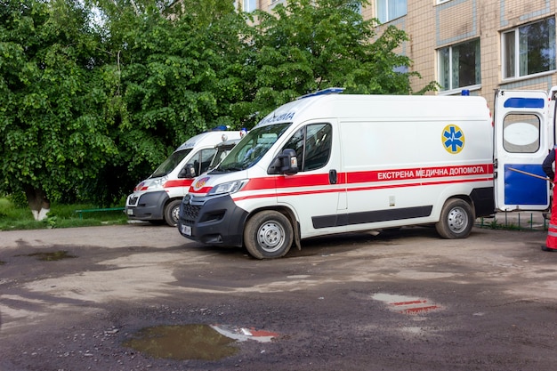 Фото Киев. украина 06.08.2021. машины скорой помощи возле зеленых деревьев. лужи после дождя.