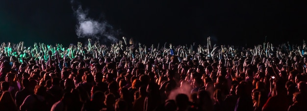 KIEV, UKRAINE - Jul 01, 2017: Crowd of spectators at a concert at night lit by a spotlight from the stage against a background of nature and dramatic storm clouds