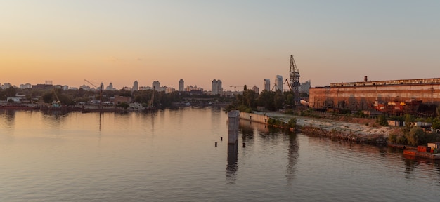 KIEV, UKRAINE - May 30, 2018: Industrial district of Kiev in Podil district. Dnieper and the river port. View from cable-stayed Rybalsky bridge in the evening during sunset