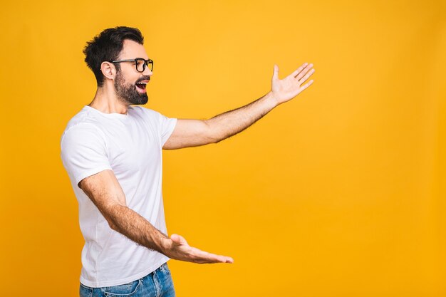 Kijk daar! gelukkig jonge knappe man in casual wijzend weg naar copyspace en glimlachen terwijl staande geïsoleerd op gele achtergrond.