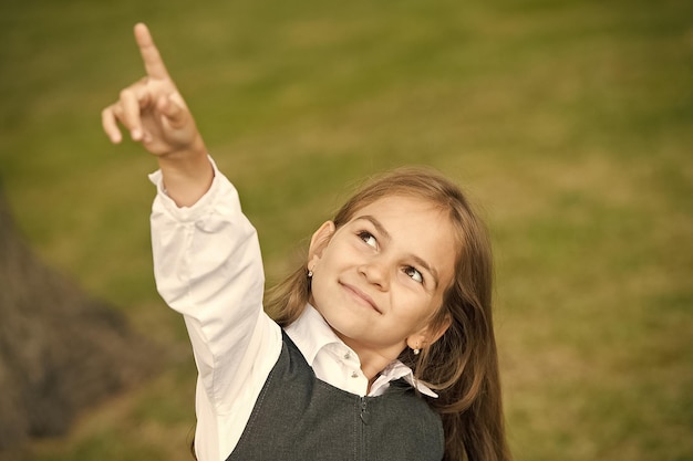 Kijk daarginds Kindje wijst met de vinger omhoog in de buitenlucht Klein meisje draagt schooluniform Terug naar school Kindereducatie Naschoolse opvang en kinderopvang Kinderopvang Kinderopvang Weinig gaat een lange weg