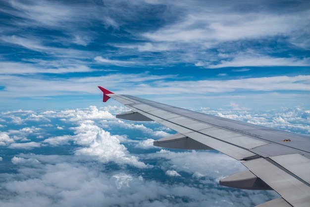 Kijk door het vliegtuigraam en de witte wolk en de blauwe lucht