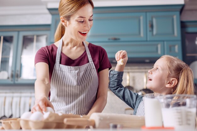 Kijk hier. Schattig klein meisje dat haar moeder een stervormig koekje laat zien, dat ze zelf heeft gemaakt, terwijl ze haar moeder hielp met het bakken van koekjes