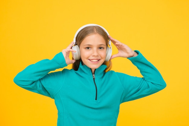 Kijk naar de muziek. Klein kind luisteren naar muziek gele achtergrond. Klein kind geniet van muziek in oortelefoons. Als muziek in mijn oren.