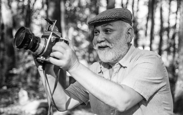 Kijk naar deze Gelukkige gepensioneerde houdt camera in de natuur professionele fotograaf met camera De fotograaf houdt DSLR-camera maakt prachtige foto's op film retro camera vrijheid man reiziger